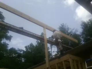 Carpenter setting a ridge beam over a new addition frame — Ice Dam Removal by Roofing Brothers in Appling