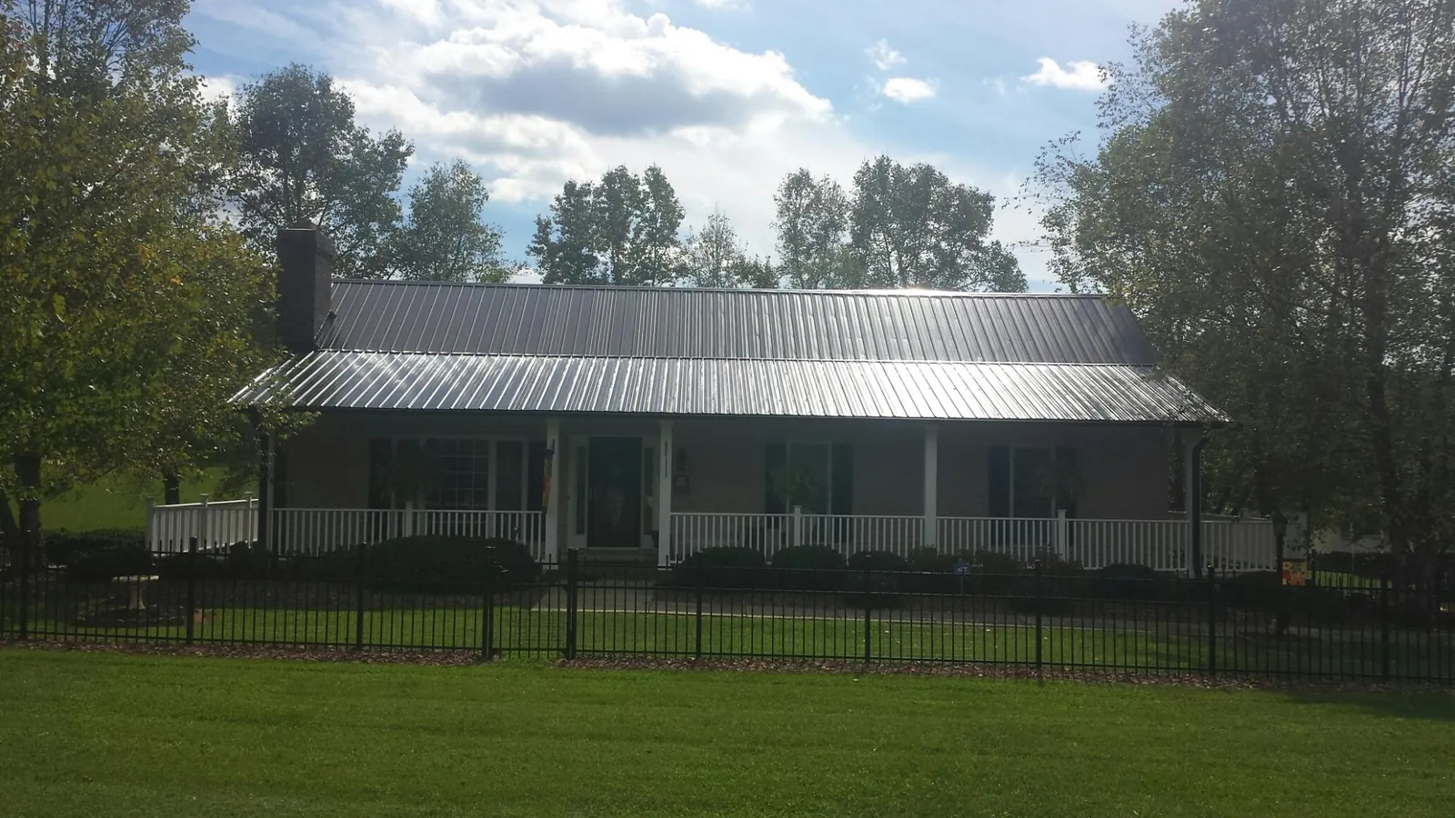 Gray metal roof on a brick ranch with a full width front porch — Gutter Guard Installation work by our crew in Appling